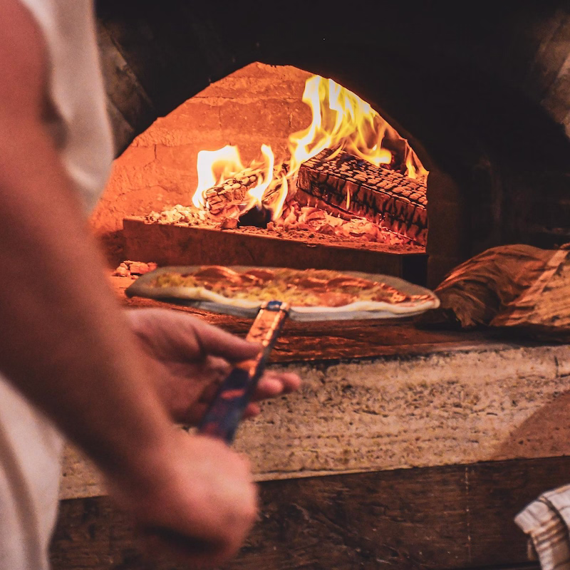 Pizza master putting pizzas in oven