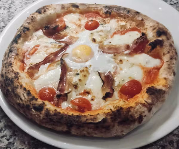 Pizza with eggs, bacon and cherry tomatoes